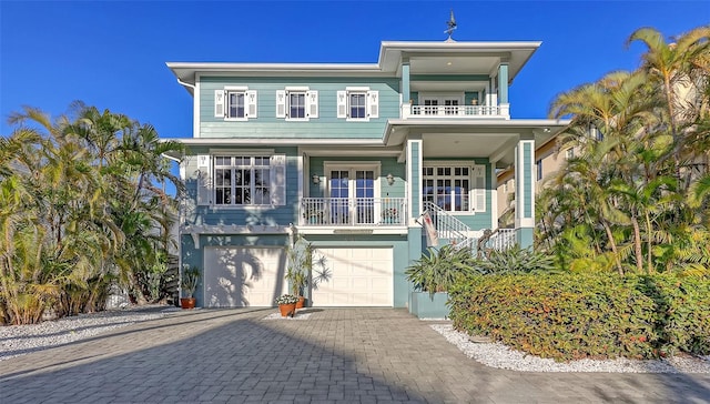 coastal inspired home featuring a balcony, decorative driveway, and a garage