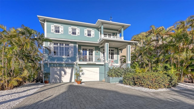 view of front of house with a garage, a porch, decorative driveway, and a balcony