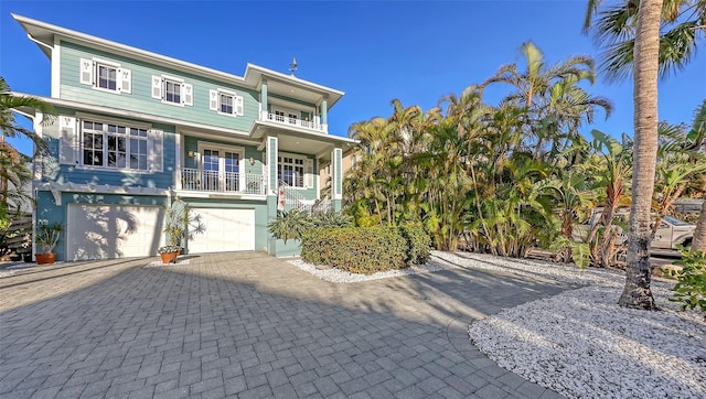 view of front of home featuring decorative driveway, a balcony, and an attached garage