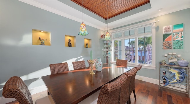 dining area with a tray ceiling, baseboards, crown molding, and hardwood / wood-style flooring