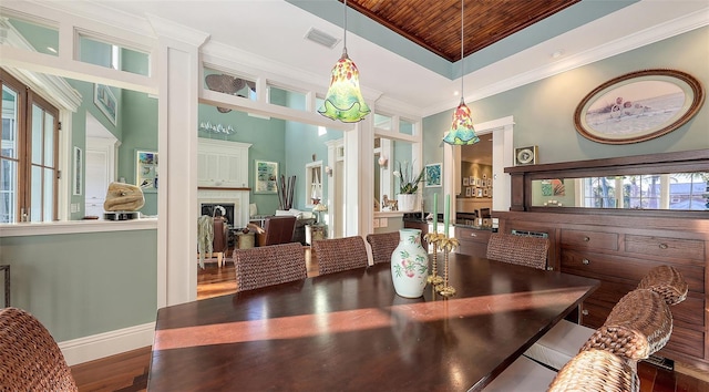 dining area with wood finished floors, visible vents, a fireplace, crown molding, and a raised ceiling