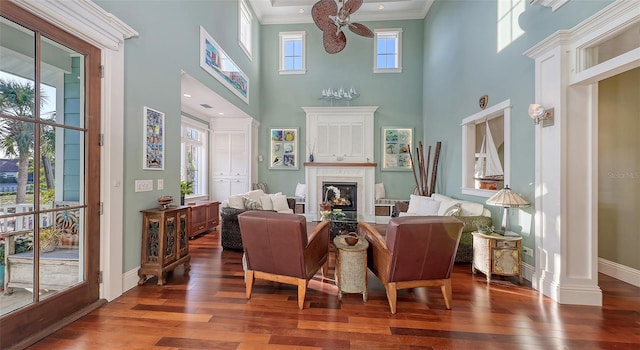 living area featuring hardwood / wood-style floors, baseboards, a glass covered fireplace, and ornamental molding