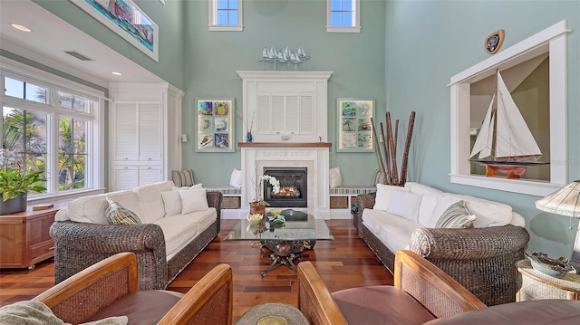 living room featuring a high end fireplace, visible vents, a high ceiling, and wood finished floors