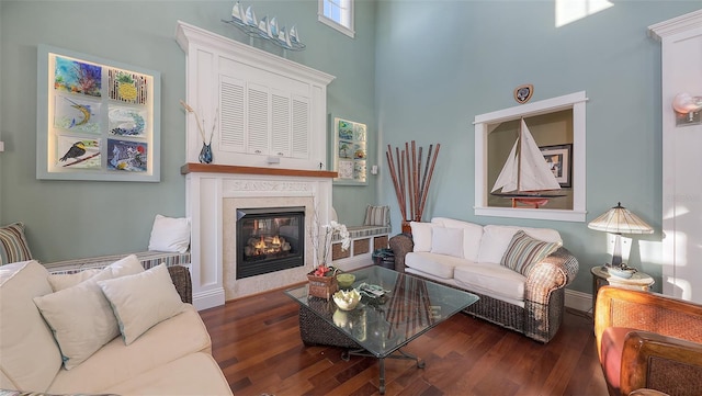 living area with a towering ceiling, wood finished floors, and a high end fireplace