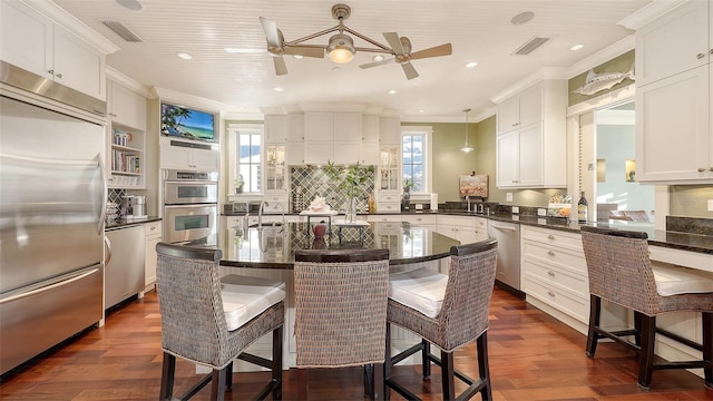 kitchen with visible vents, a breakfast bar, ornamental molding, appliances with stainless steel finishes, and a ceiling fan