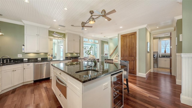 kitchen with a center island with sink, a sink, wine cooler, dishwasher, and ceiling fan