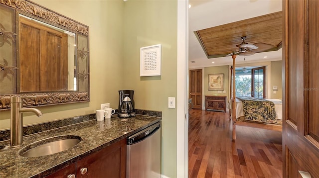 kitchen featuring dishwasher, wood finished floors, a raised ceiling, a ceiling fan, and a sink