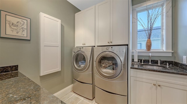 laundry area with baseboards, washing machine and dryer, light tile patterned flooring, cabinet space, and a sink