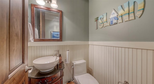 bathroom featuring a wainscoted wall, toilet, and vanity