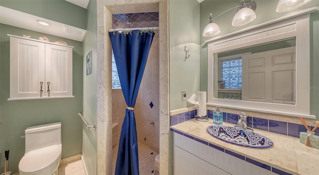 bathroom with tiled shower, toilet, and vanity