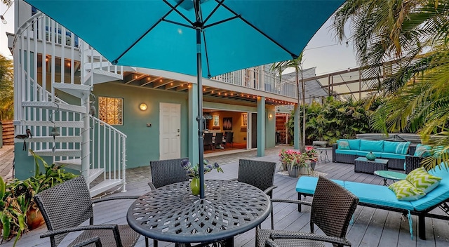 wooden deck with an outdoor living space, stairway, and outdoor dining space