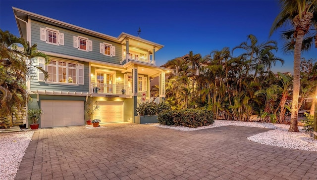 view of front of house featuring decorative driveway, a balcony, and an attached garage