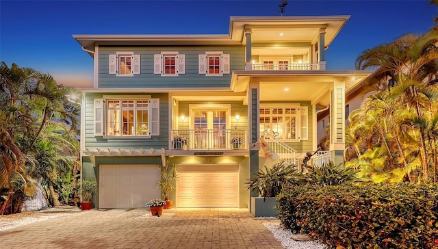 view of front of property with a balcony, decorative driveway, and a garage