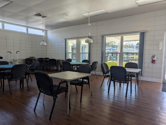 dining area featuring dark wood-type flooring, plenty of natural light, a paneled ceiling, and visible vents