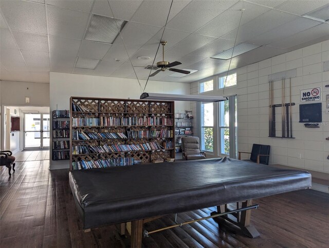 game room with billiards, a ceiling fan, wood finished floors, a drop ceiling, and tile walls