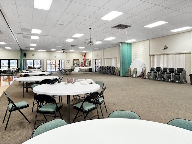 carpeted dining space with a paneled ceiling