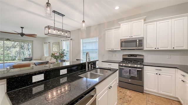 kitchen with a sink, tasteful backsplash, appliances with stainless steel finishes, white cabinets, and ceiling fan