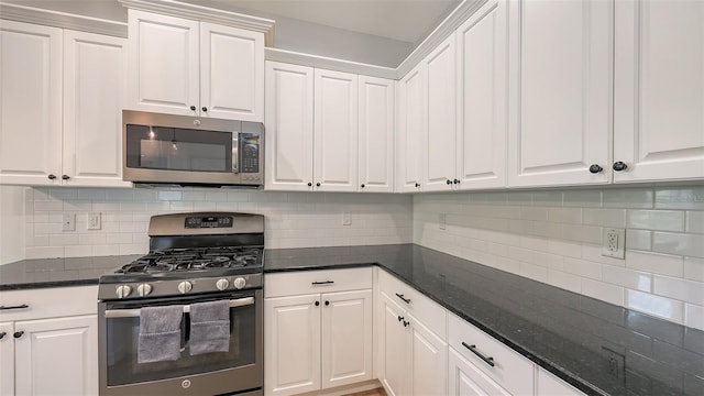 kitchen featuring dark stone countertops, decorative backsplash, appliances with stainless steel finishes, and white cabinetry