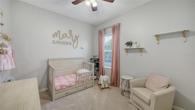 carpeted bedroom with baseboards, a ceiling fan, and a nursery area