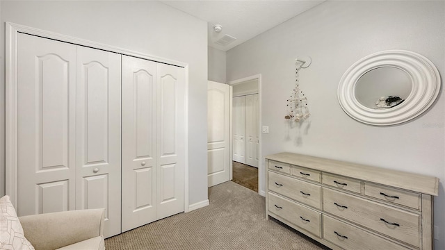 bedroom featuring a closet, visible vents, and light colored carpet