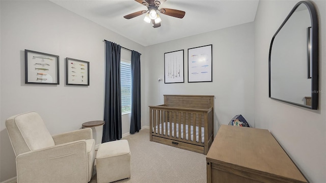 bedroom with a crib, carpet, and a ceiling fan