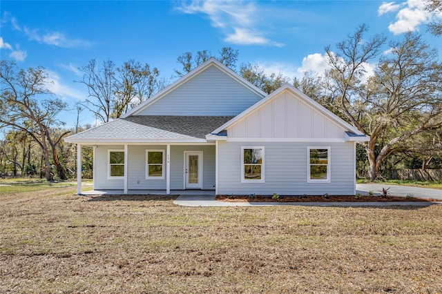 view of front facade featuring board and batten siding, a shingled roof, and a front lawn