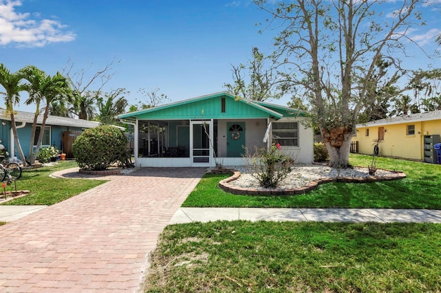 view of front of property with decorative driveway, stucco siding, a front lawn, and a sunroom