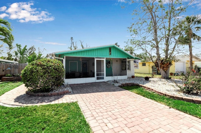 rear view of property with a yard, fence, and a sunroom