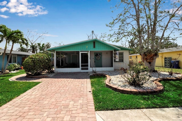 view of front of property featuring a front yard and a sunroom