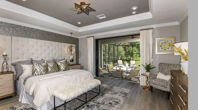 bedroom featuring visible vents, crown molding, a tray ceiling, and wood finished floors