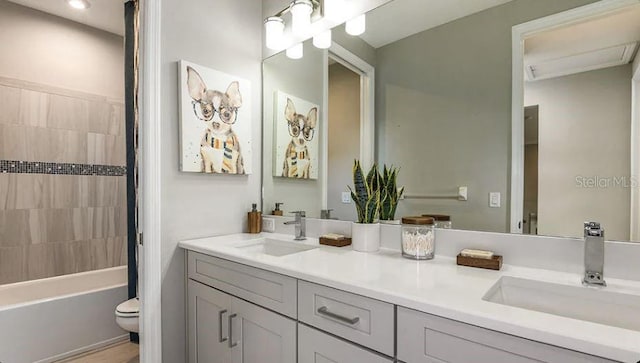 bathroom featuring double vanity, toilet, shower / bathing tub combination, and a sink