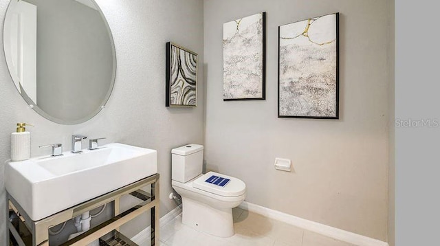 bathroom featuring tile patterned flooring, toilet, baseboards, and a sink