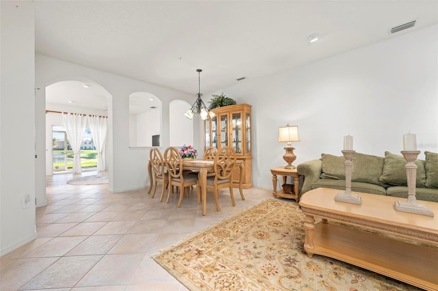 living room featuring light tile patterned floors, baseboards, visible vents, arched walkways, and a chandelier