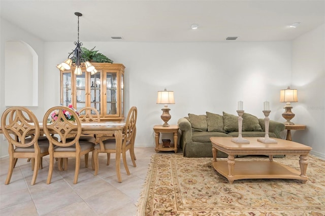 living area with light tile patterned floors, visible vents, baseboards, and an inviting chandelier