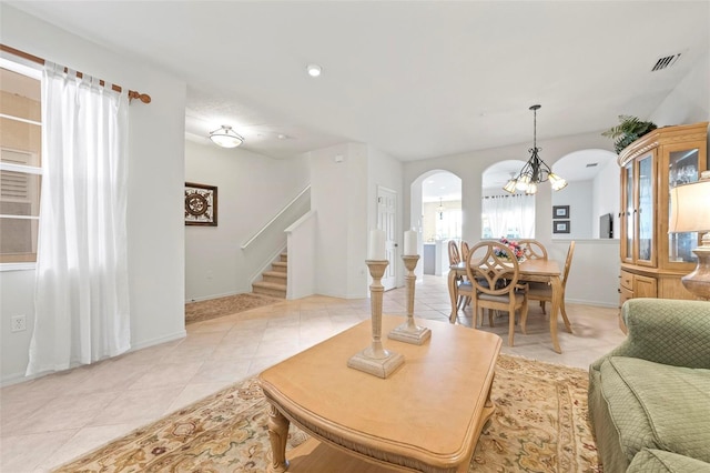 living room with arched walkways, light tile patterned floors, stairs, and visible vents