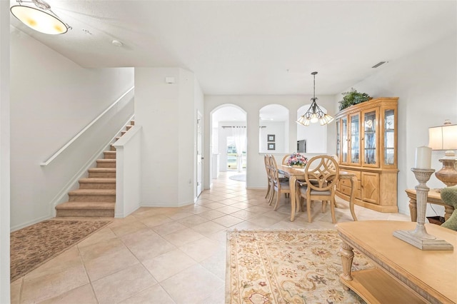 dining area featuring baseboards, a chandelier, stairs, light tile patterned floors, and arched walkways