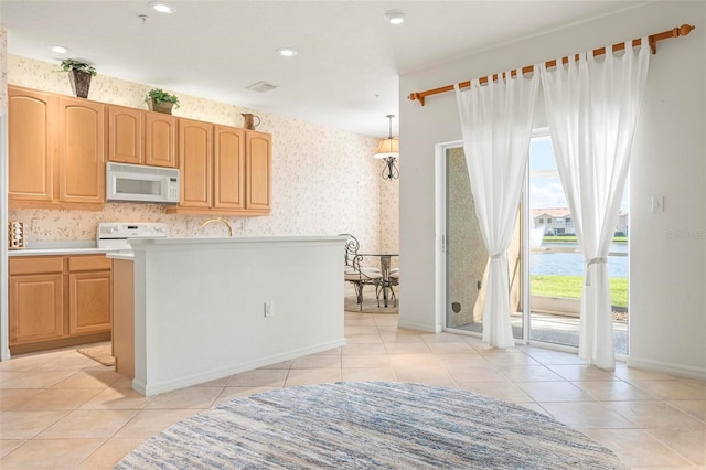 kitchen with white microwave, wallpapered walls, light countertops, light tile patterned floors, and stove