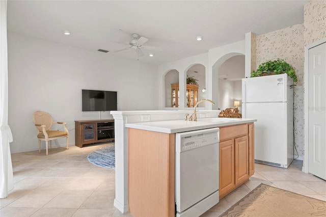 kitchen featuring light brown cabinets, a ceiling fan, a sink, white appliances, and light tile patterned flooring