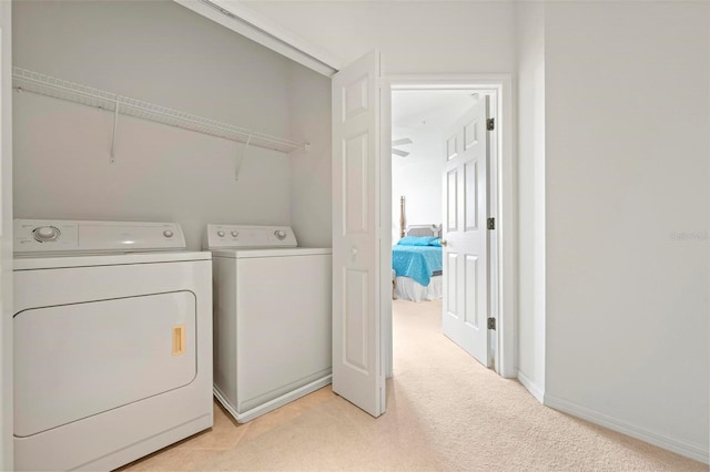 clothes washing area featuring laundry area, baseboards, independent washer and dryer, and light carpet