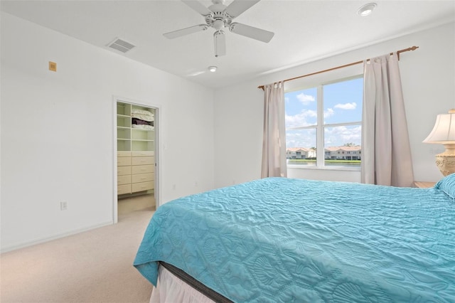 bedroom featuring a ceiling fan, carpet, visible vents, baseboards, and a walk in closet