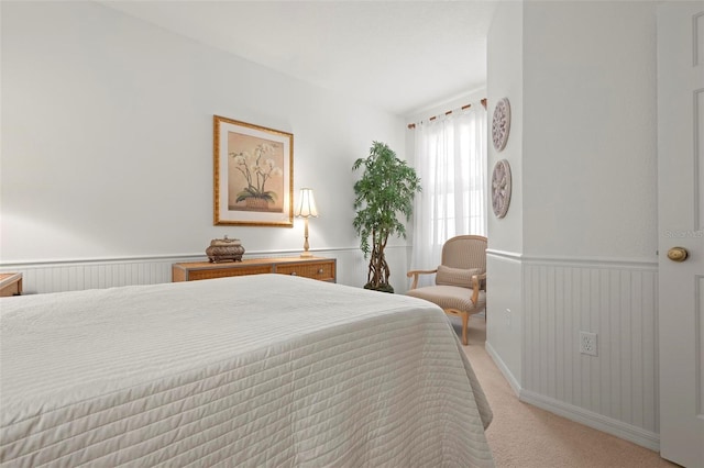 bedroom with wainscoting and light carpet