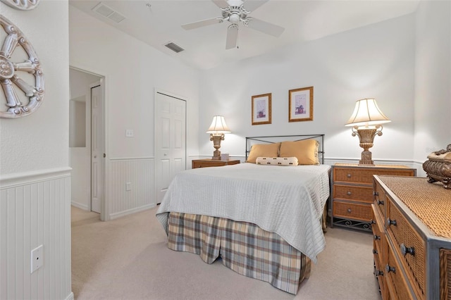 bedroom with visible vents, light colored carpet, a wainscoted wall, and a closet