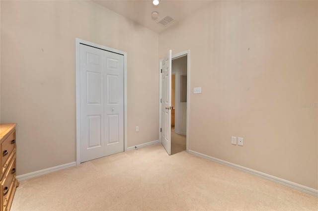 unfurnished bedroom with visible vents, light colored carpet, baseboards, and a closet