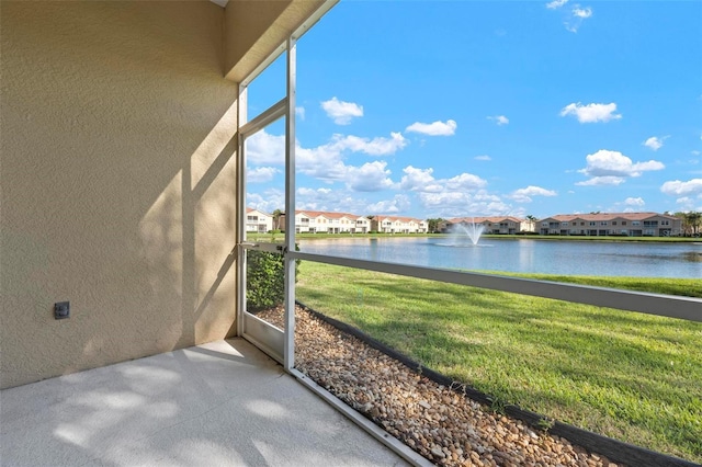 unfurnished sunroom with a residential view and a water view