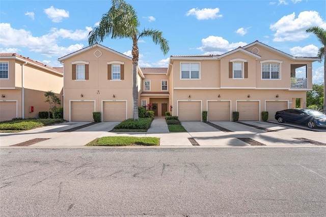 multi unit property featuring stucco siding, driveway, and an attached garage