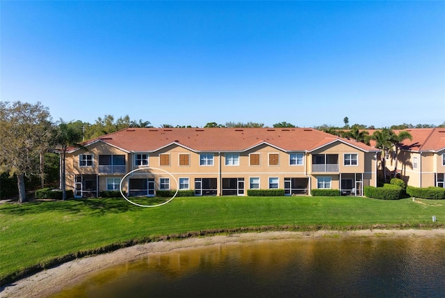 back of property with a yard, a water view, and stucco siding