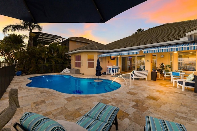 pool at dusk featuring a patio area, fence, and a fenced in pool