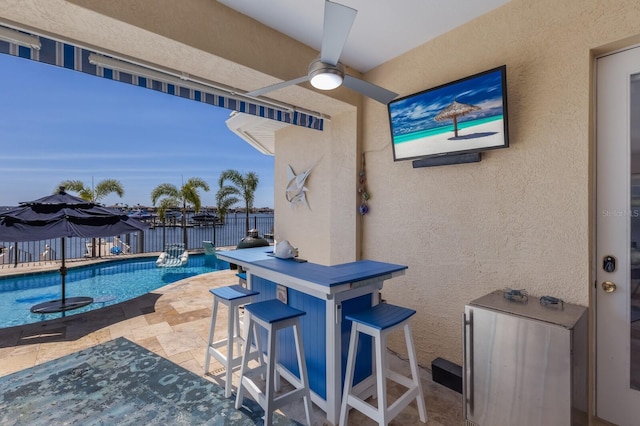 view of patio featuring outdoor dry bar, fence, a fenced in pool, and ceiling fan