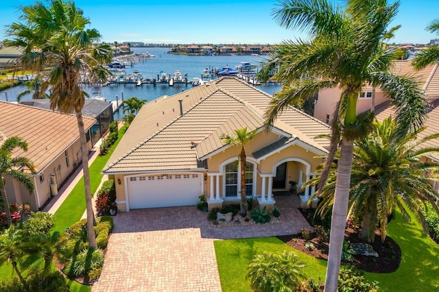 1009 3rd St E, Palmetto, FL 34221 - view of front of house with a tile roof, stucco siding, a garage, decorative driveway, and a water view
