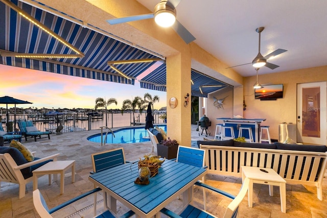 1009 3rd St E, Palmetto, FL 34221 - pool at dusk with a ceiling fan, a patio, outdoor dining area, and a water view